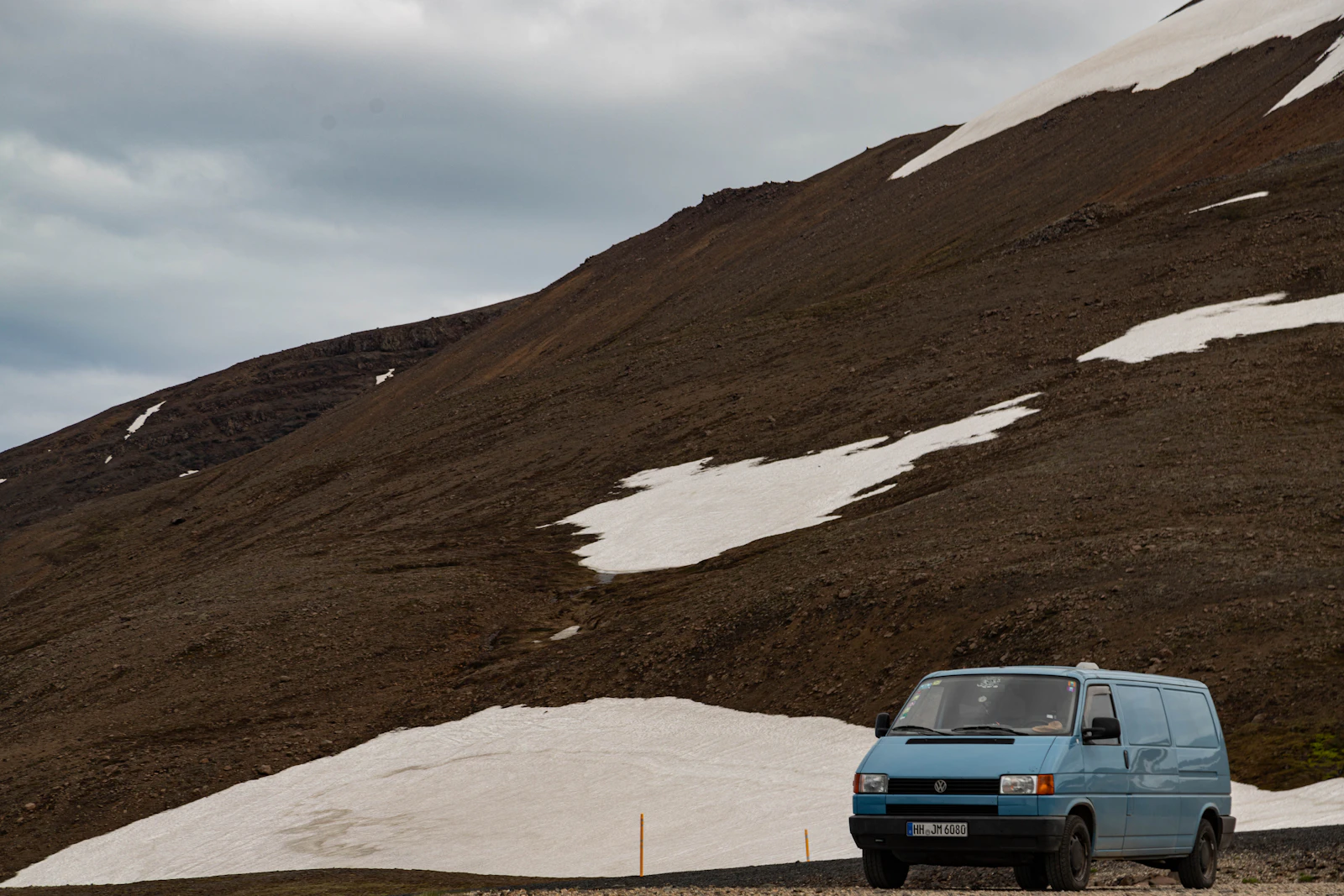 A blue van parked beside an Icelandic mountain