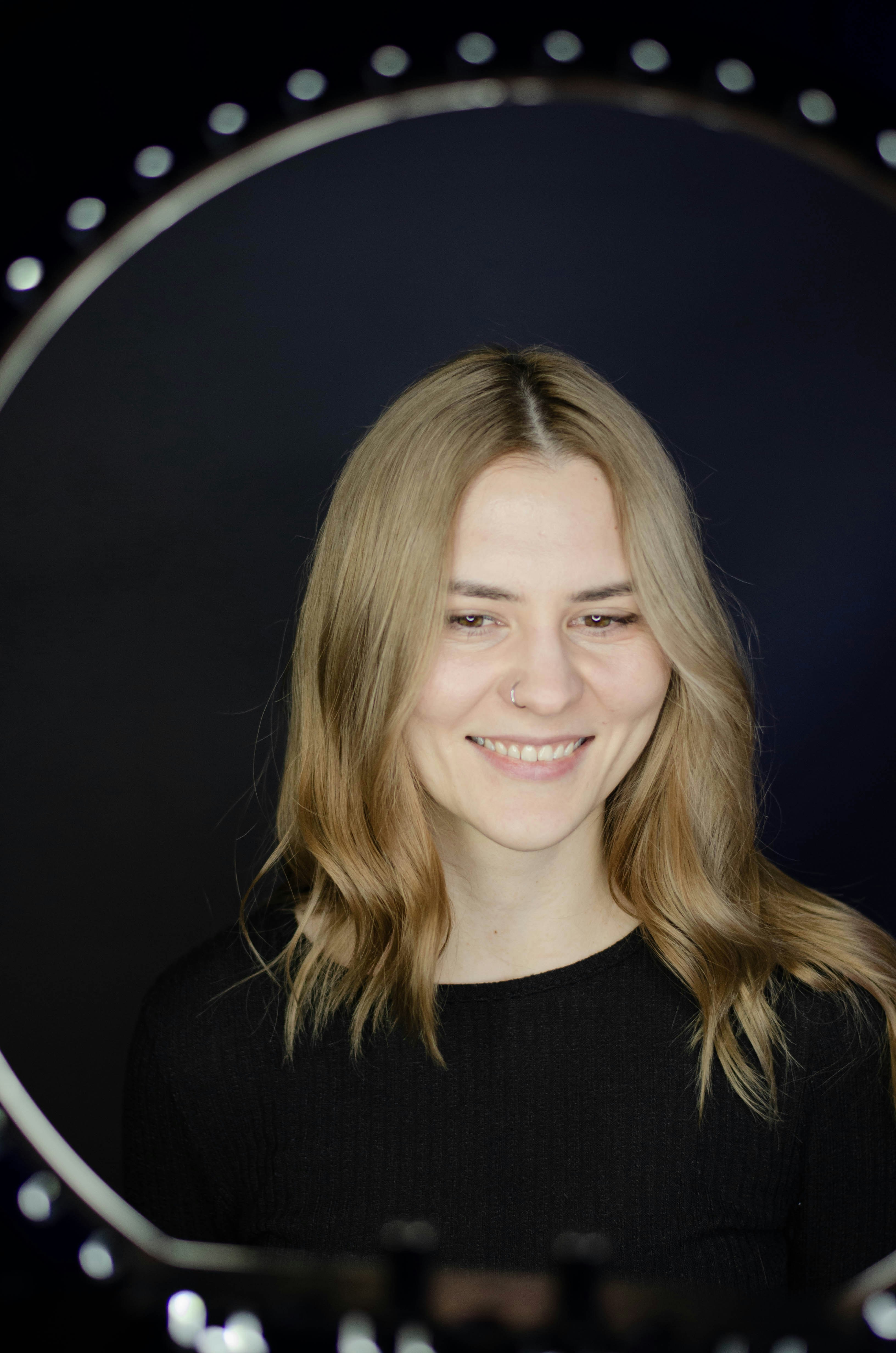 a woman with long blonde hair smiling in front of a mirror