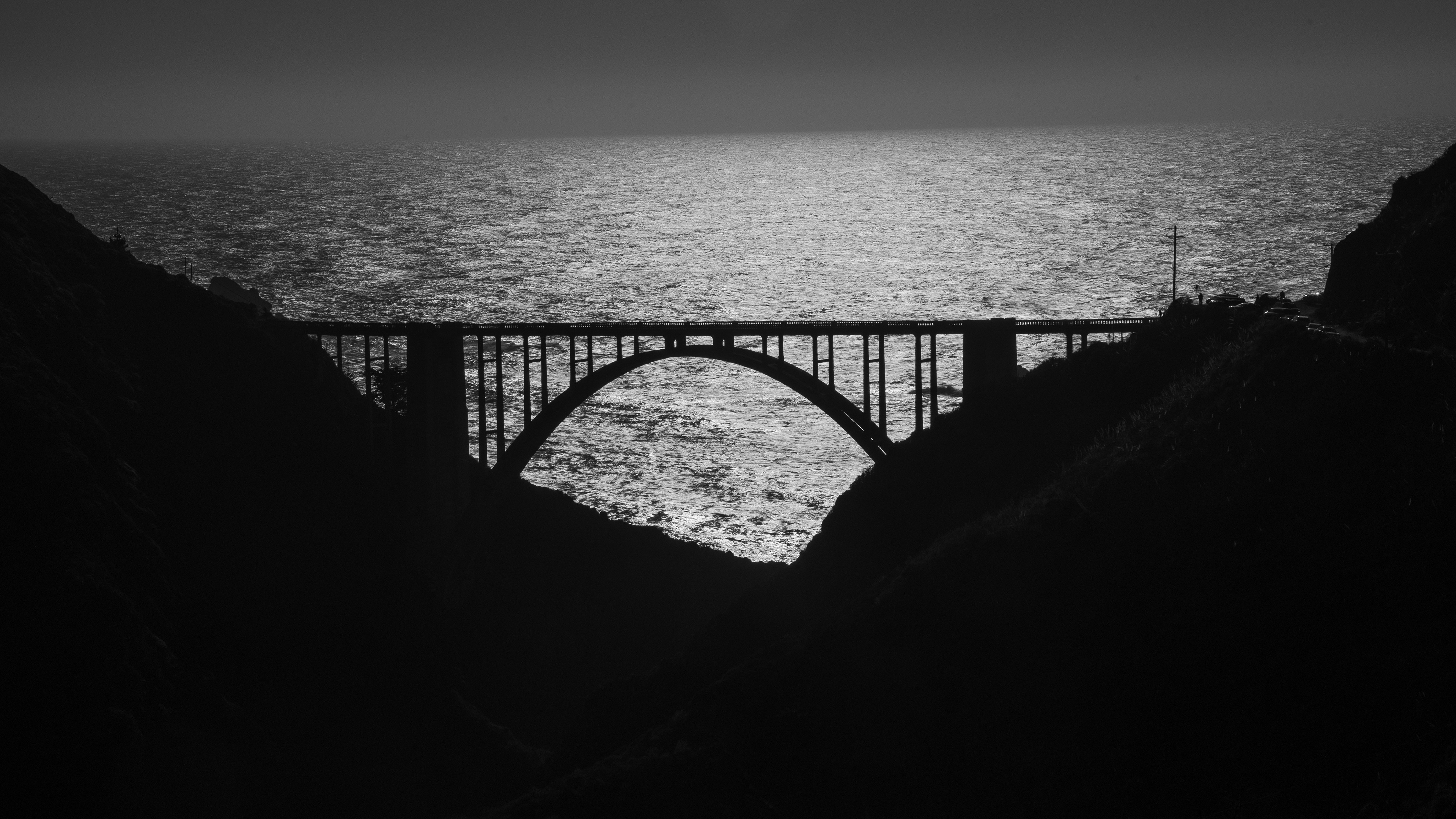 une photo en noir et blanc d’un pont au-dessus d’un plan d’eau