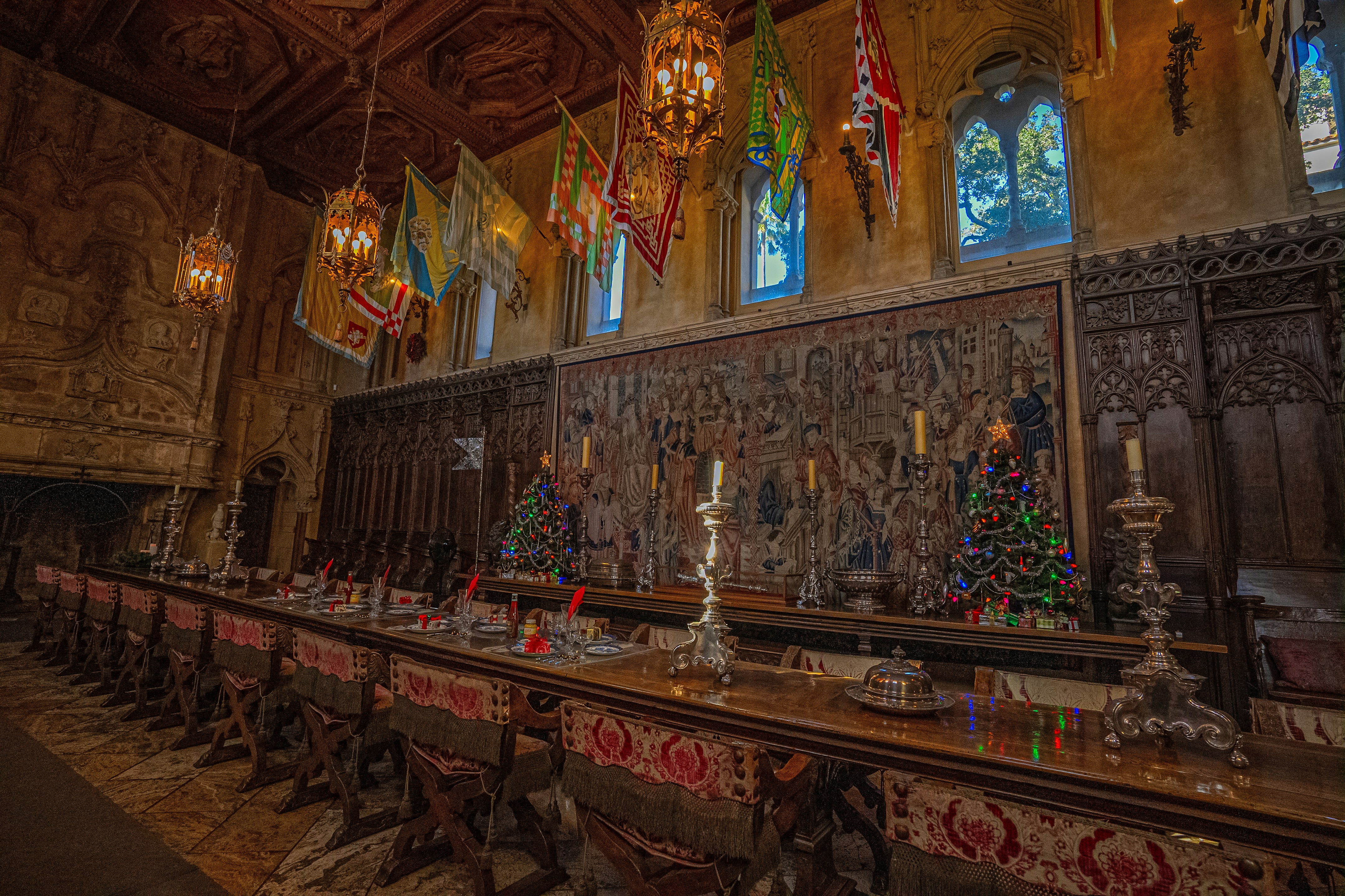 A long banquet table set beneath hanging banners in a carved, wood-paneled hall
