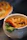 A close-up of a handmade ceramic bowl filled with fresh soup, showcasing rich glazes in warm tones.