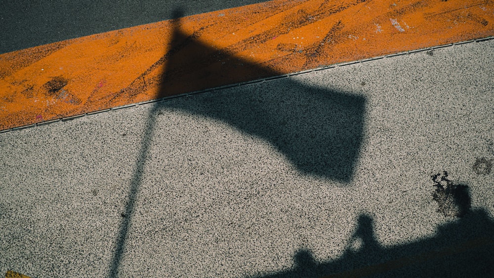 a shadow of a street sign on a sidewalk