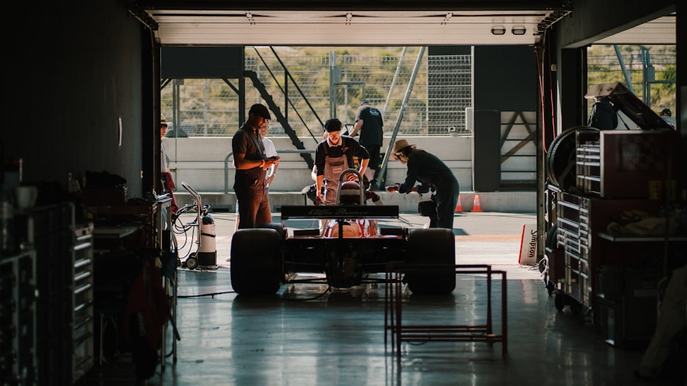 a group of people standing around a car in a garage