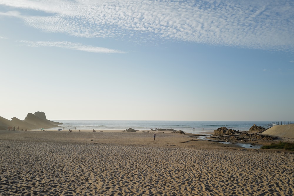 a sandy beach next to the ocean under a blue sky