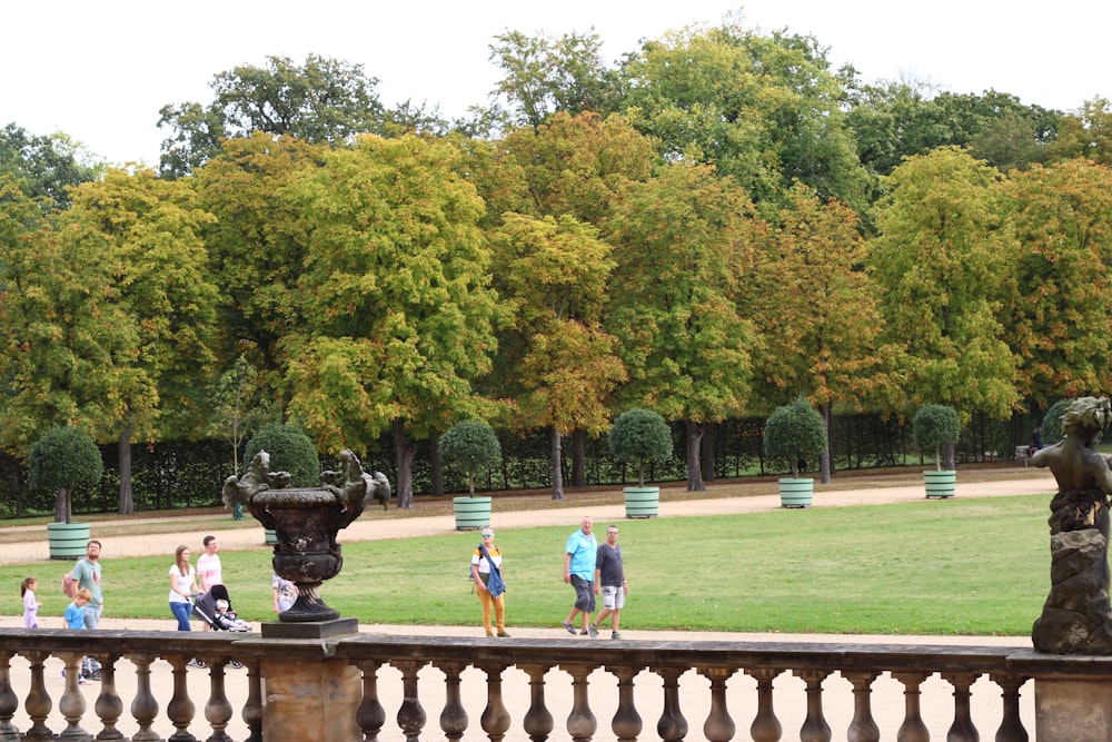 a group of people walking around a lush green park