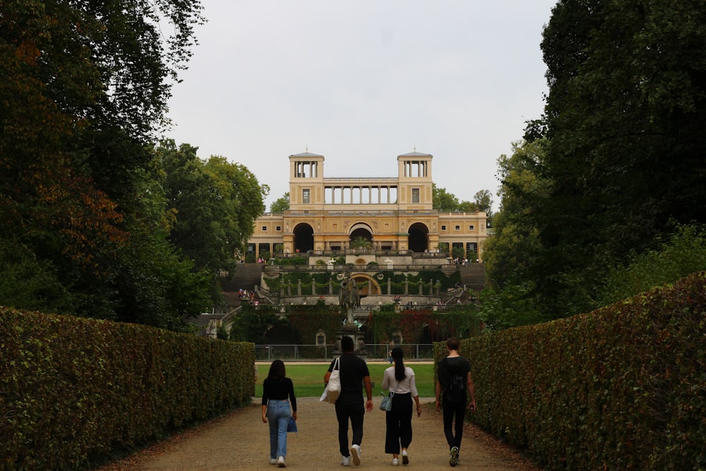 a group of people walking down a path in front of a building