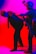 A person in tactical gear and night vision goggles is detaining another person dressed in a suit. The scene is dramatically lit with intense red and blue lighting, creating a high-contrast and tense atmosphere.
