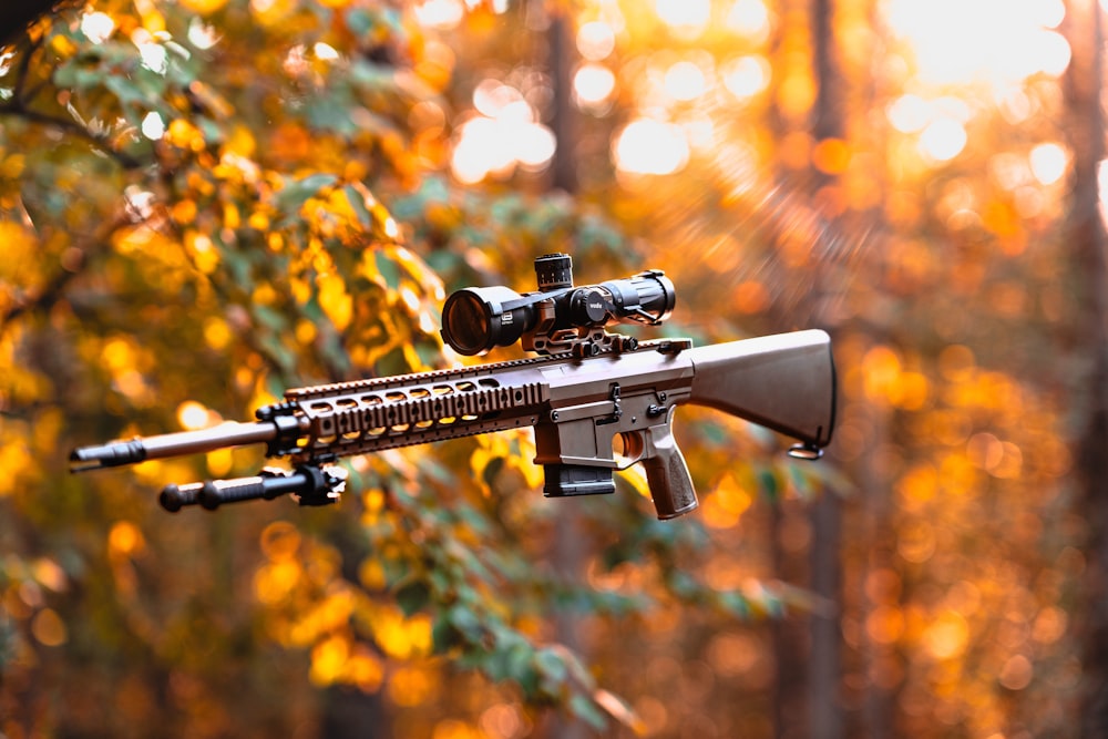 a rifle with a scope attached to it in the woods