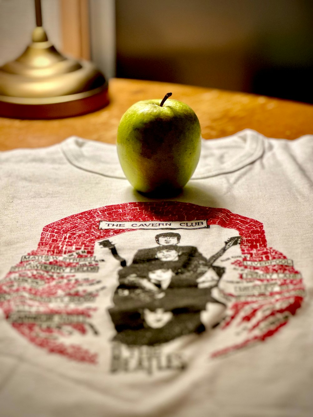 a green apple sitting on top of a white shirt