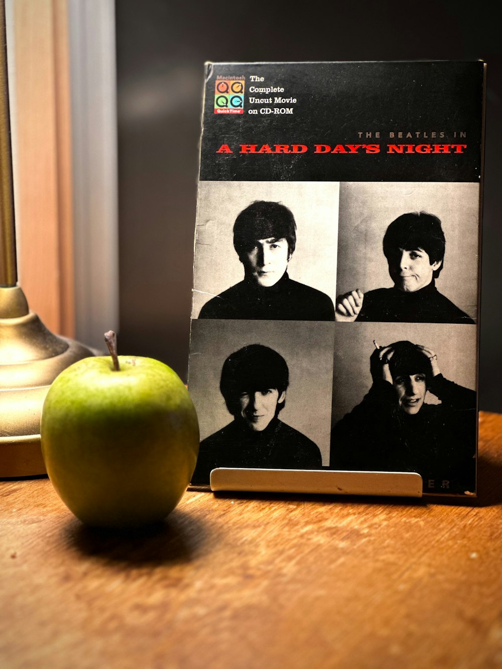 a green apple sitting next to a book on a table