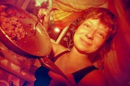 A joyful person holding a meal prep container, smiling in a bright kitchen.