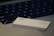 A close-up view of a laptop keyboard with a credit card resting on the surface. The credit card is white and features the logos of Goldman Sachs and Mastercard.