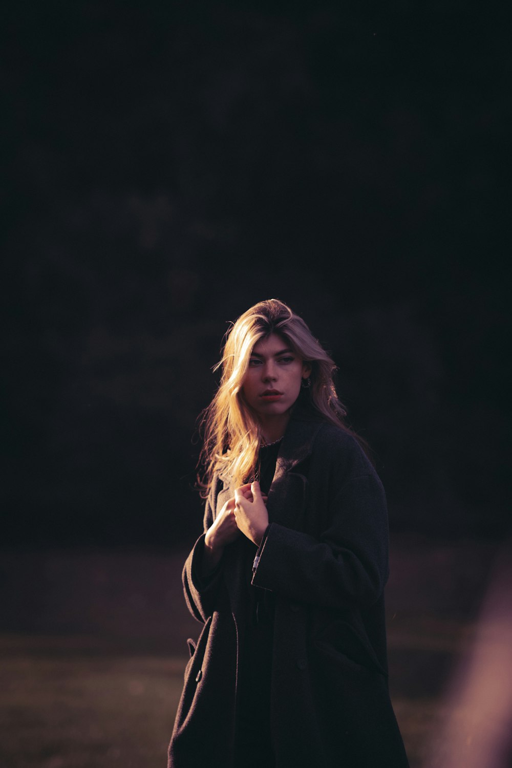 a woman standing in a field with her hands together