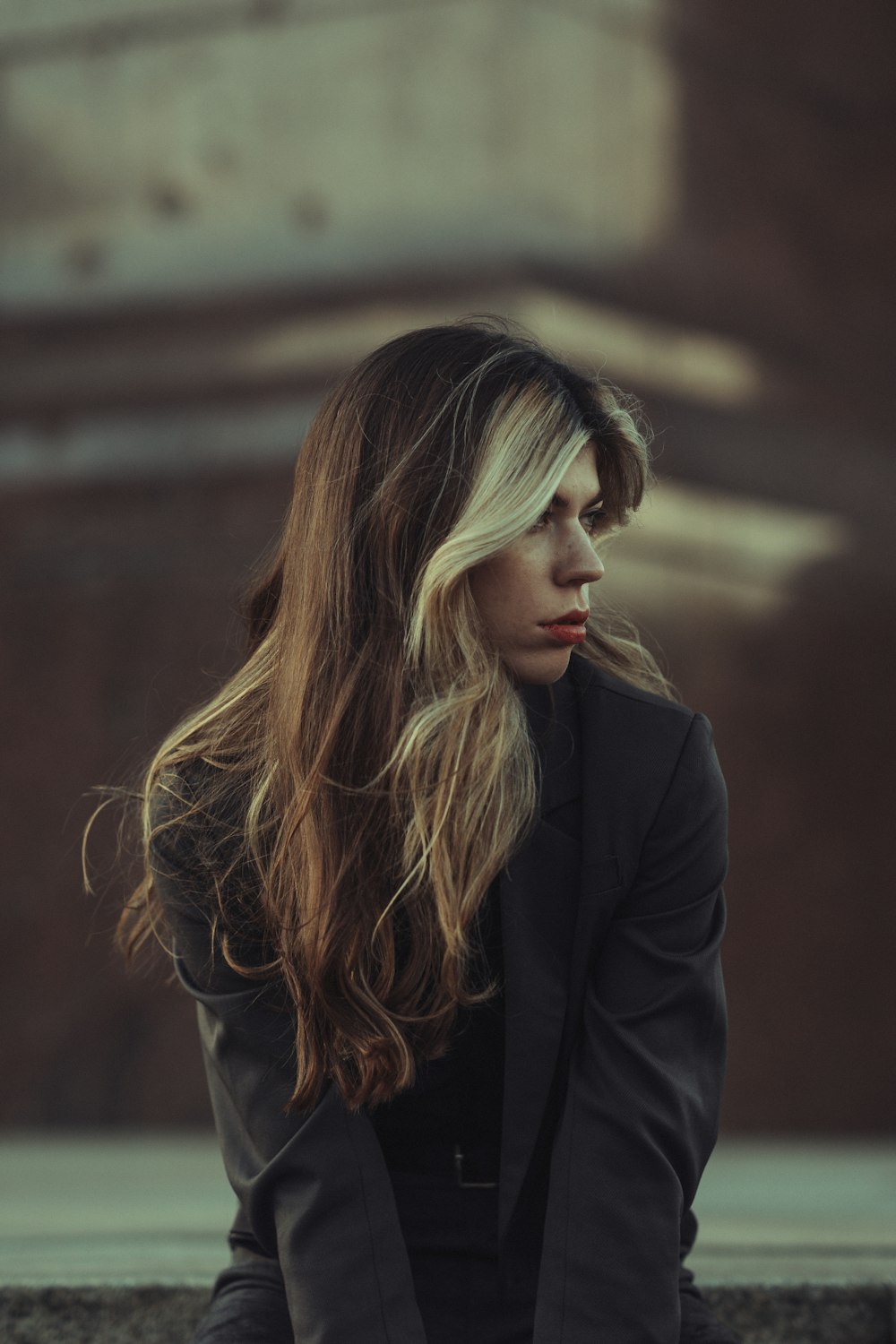 a woman with long hair sitting on a ledge