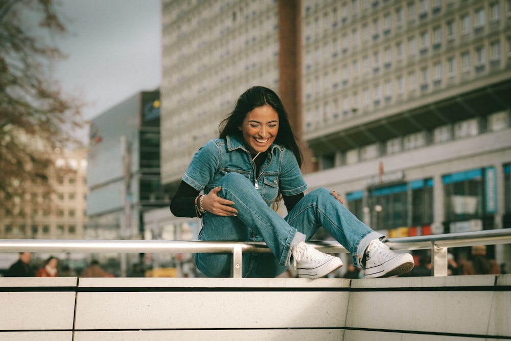 a woman sitting on a ledge in a city