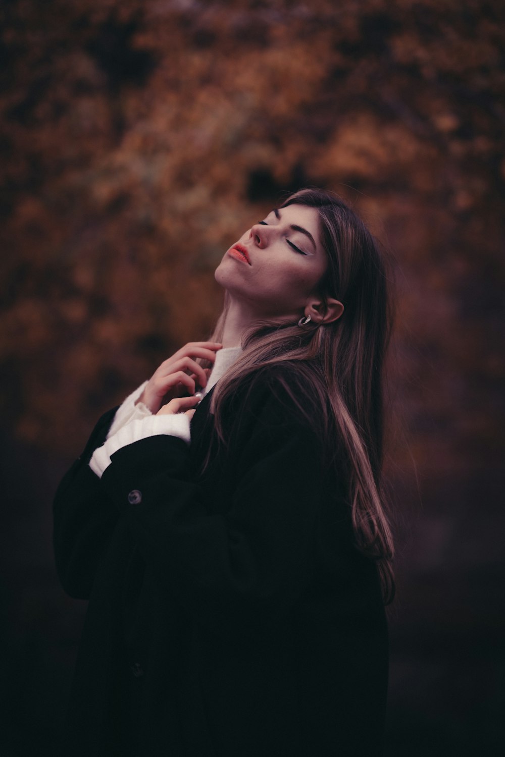 a woman standing in front of a tree with her eyes closed