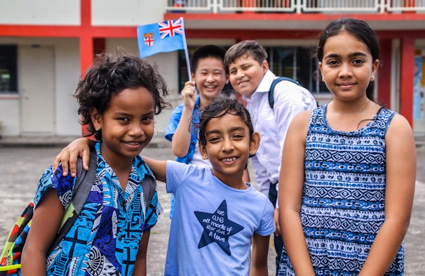 A diverse group of smiling young students engaged in a lively outdoor learning activity.