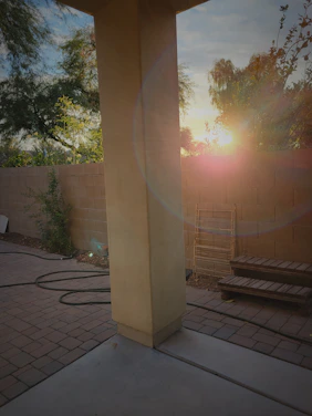 A warm sunset casting golden light over a freshly built wooden deck and fence surrounding a cozy backyard.