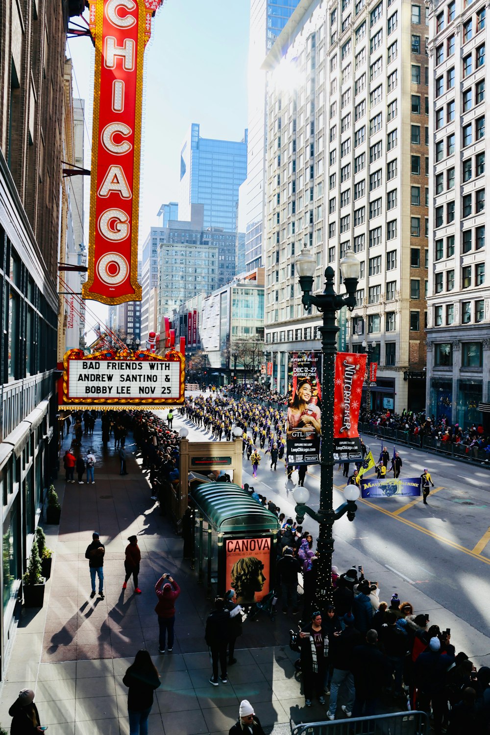 a crowd of people walking down a street next to tall buildings