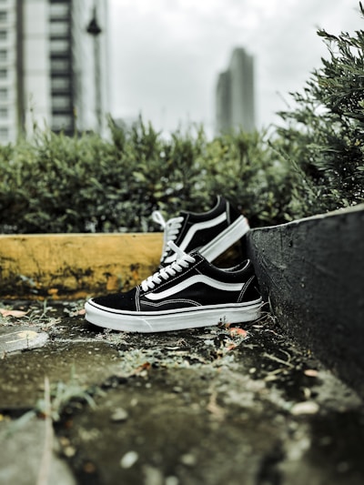 A pair of stylish, durable sneakers resting on a concrete ledge with a blurred cityscape background.