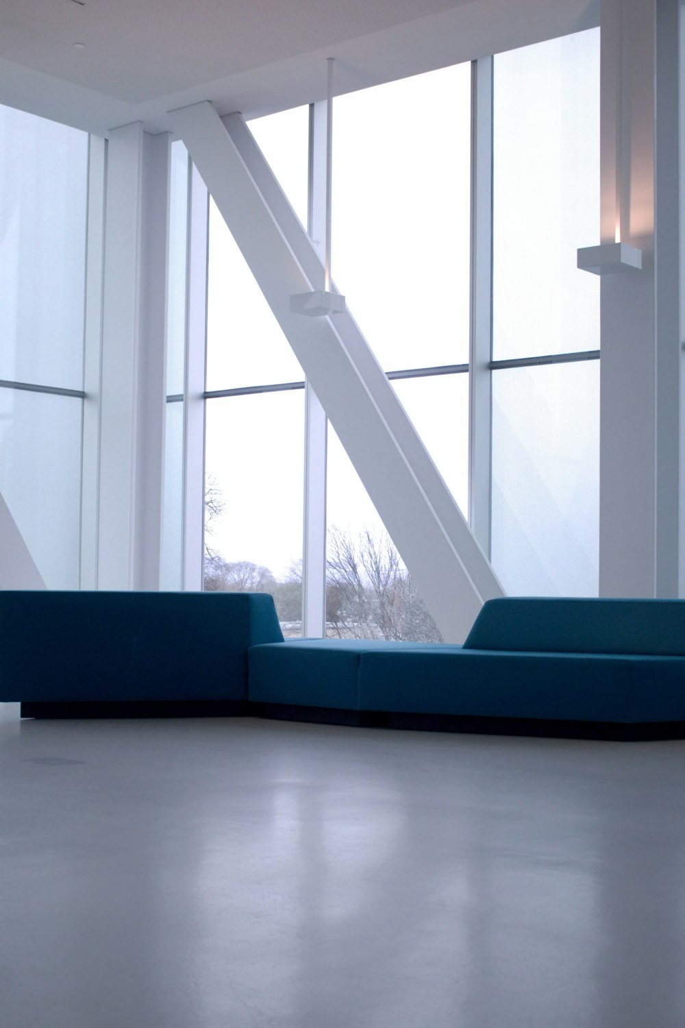 a blue couch sitting in front of large windows