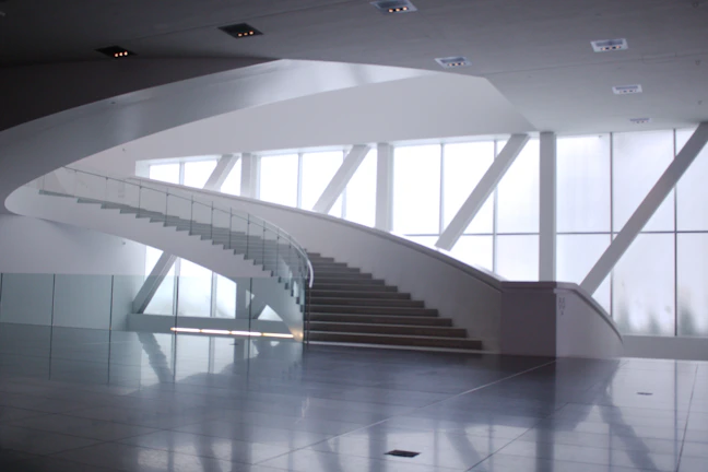 Bright modern floating staircase with sleek glass railing in a sunlit living room
