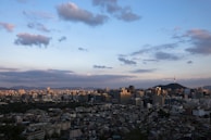 Panoramic shot of Gurugram skyline from a high-rise apartment balcony at dusk, with warm golden hues.