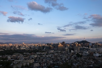 Panoramic shot of Gurugram skyline from a high-rise apartment balcony at dusk, with warm golden hues.