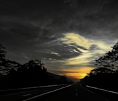 A highway stretching through a rural landscape at sunset.