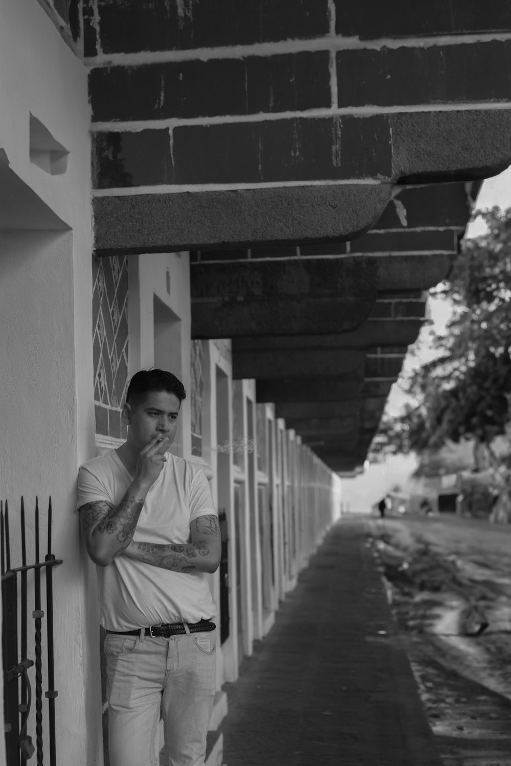 a man leaning against a wall with his hand on his face