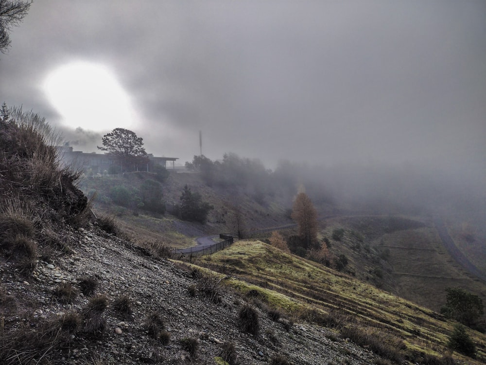 a foggy hillside with a house on top of it