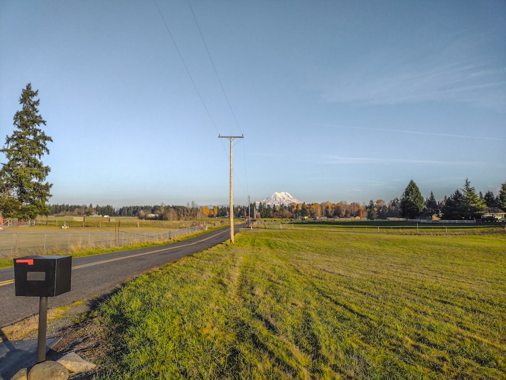 a rural road with a large field of grass next to it