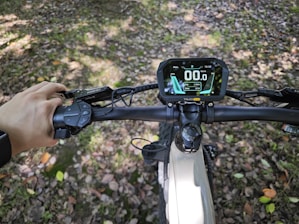 A rider adjusting a bright red speedometer on their electric bike.