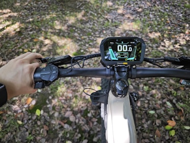 A rider adjusting a bright red speedometer on their electric bike.