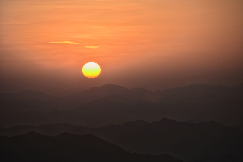 the sun is setting over a mountain range