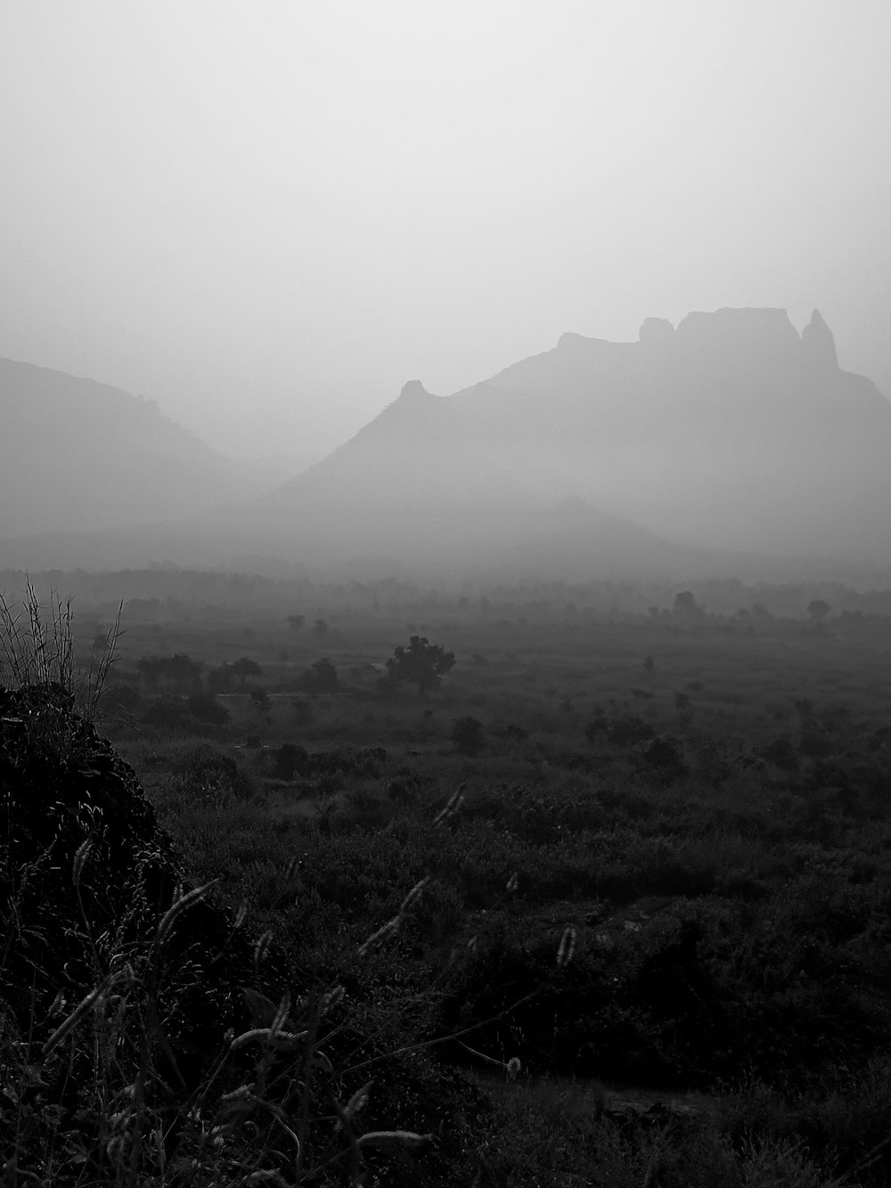 a black and white photo of mountains in the fog