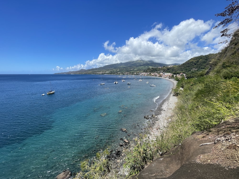 a beach with boats in the water and a hill in the background