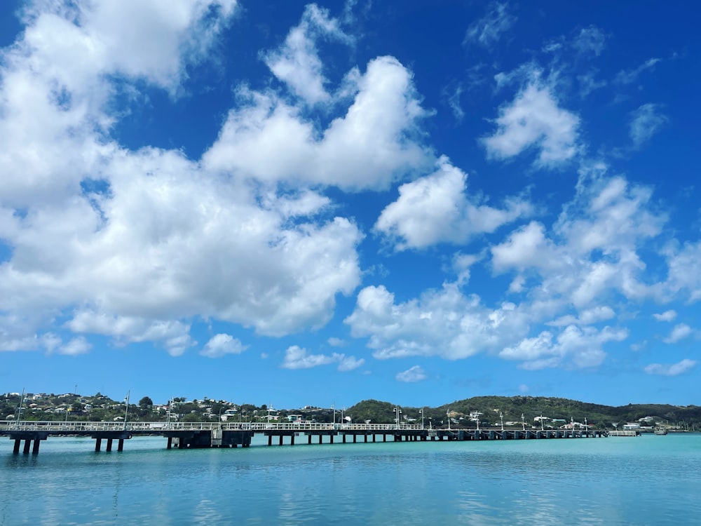 a bridge over a body of water under a cloudy blue sky