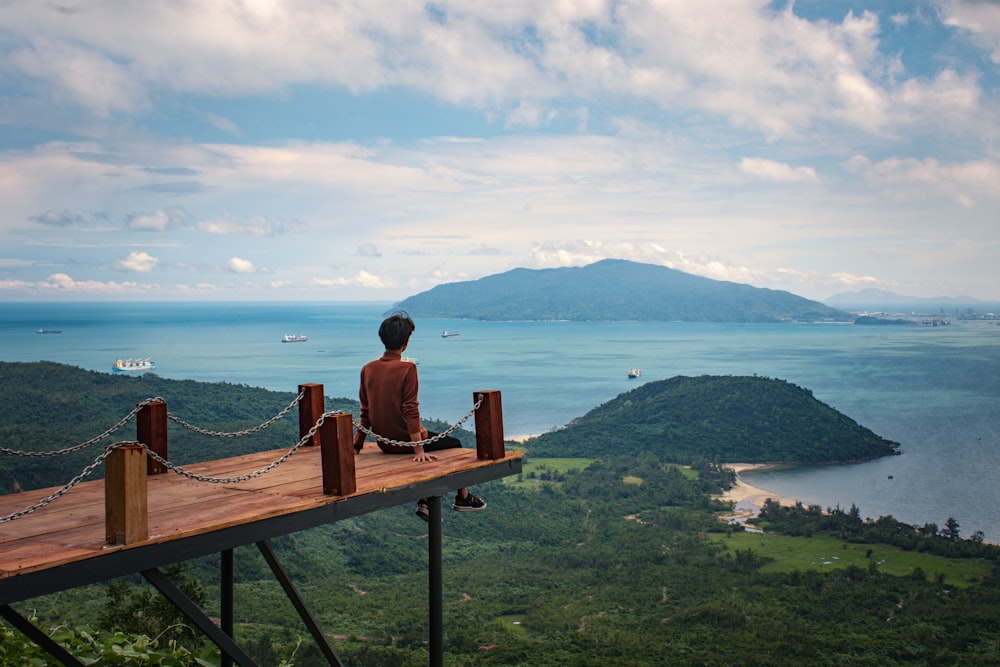 a person sitting on a wooden platform overlooking a body of water