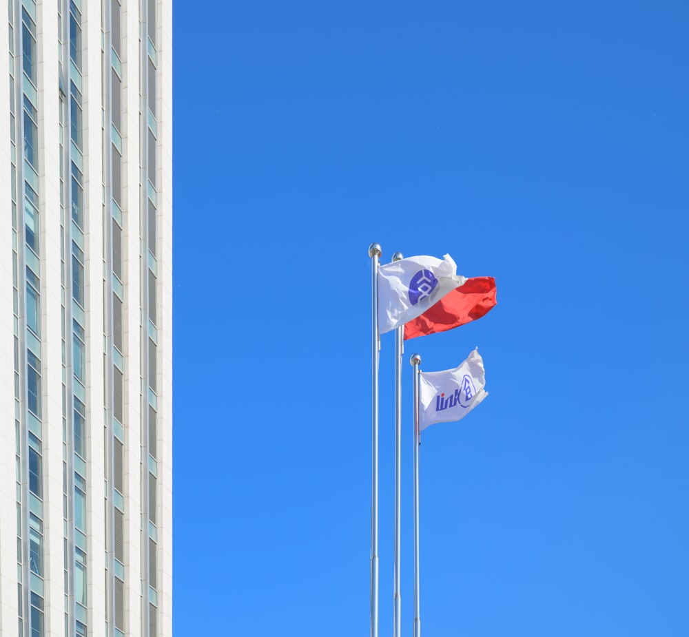 two flags flying next to each other in front of a tall building