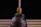 Close-up of a honey jar with honey dripping from a wooden dipper outdoors
