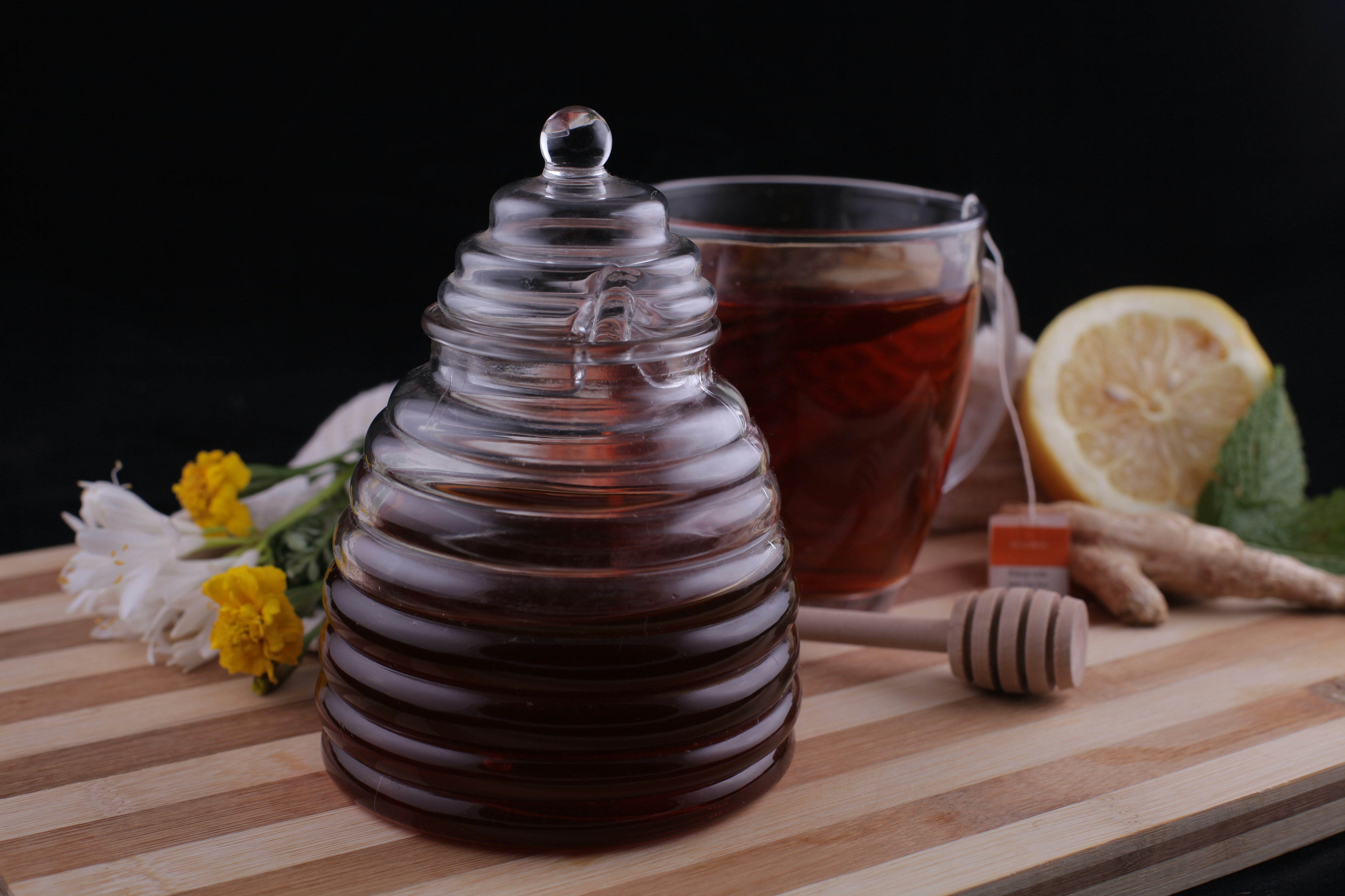 a jar of honey sits on a cutting board next to a cup of tea