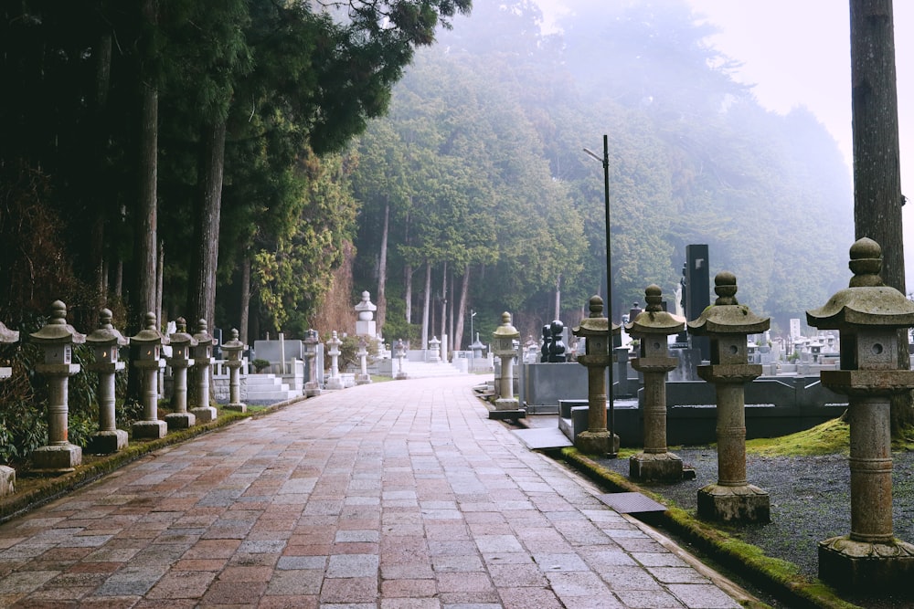 a brick walkway with a row of stone pillars on each side of it