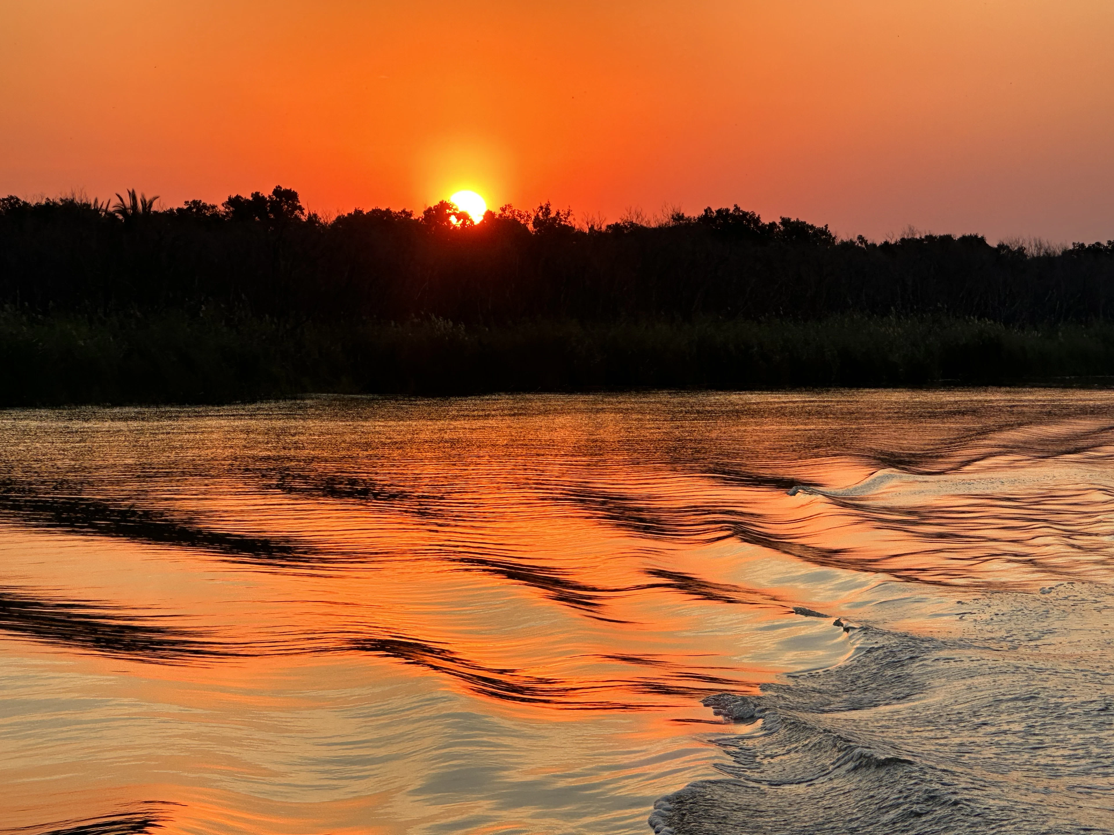 Saulėlydis virš St Lusijos estuarijos, žvelgiant iš plaukiančios valties
