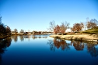 A serene lake reflecting autumn-colored trees in a peaceful English park.