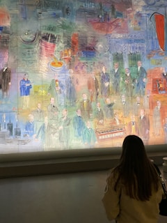 A large, colorful mural depicting historical figures and industrial scenes. Figures in period clothing are standing in a line with various industrial backgrounds like machinery and buildings. The artwork includes vibrant use of colors, combining scenes of innovation and history.