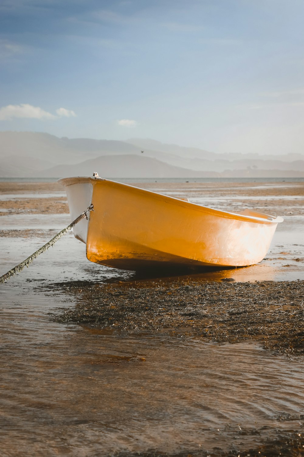 a yellow boat sitting on top of a sandy beach