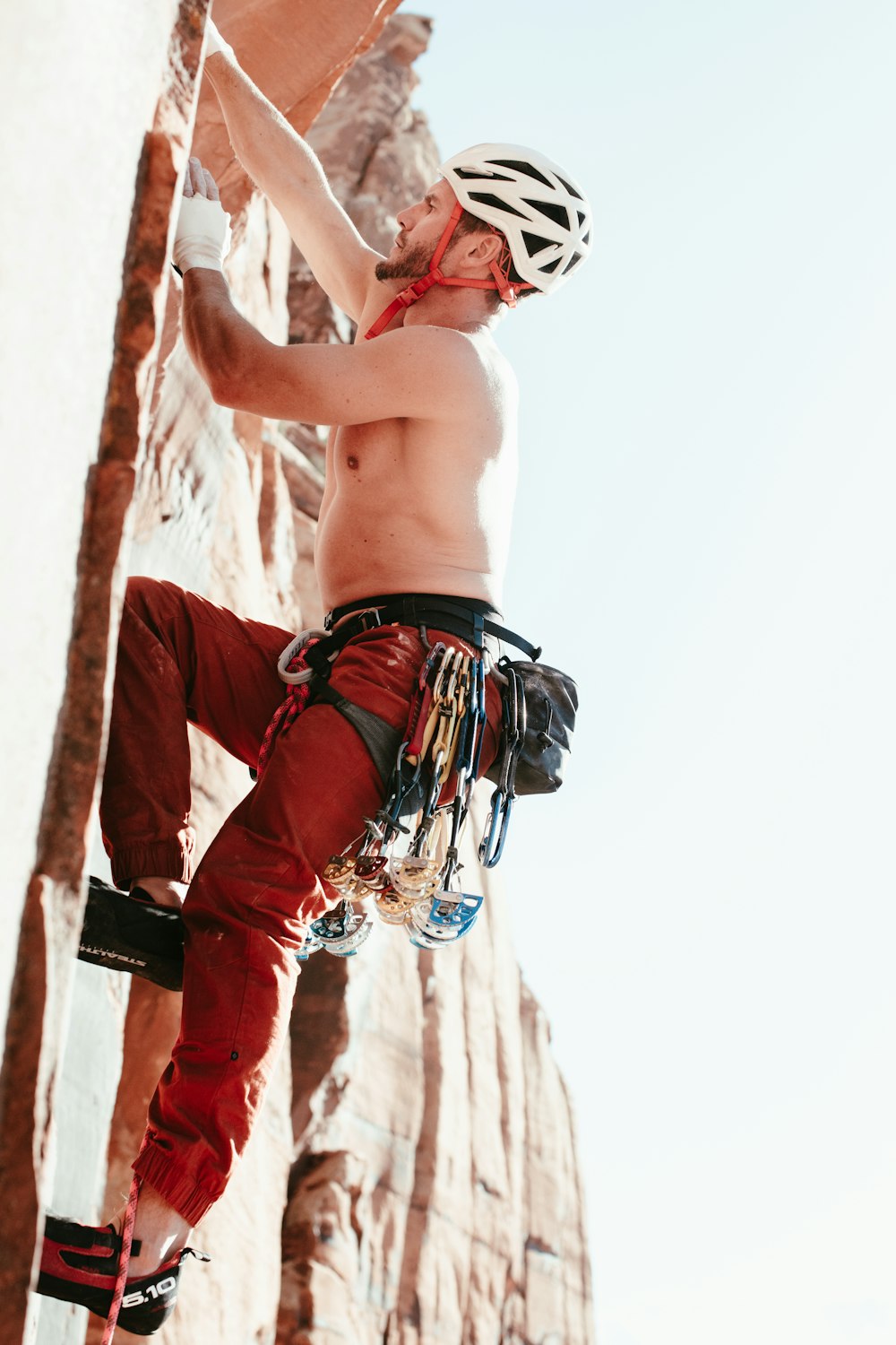 a shirtless man climbing up the side of a mountain