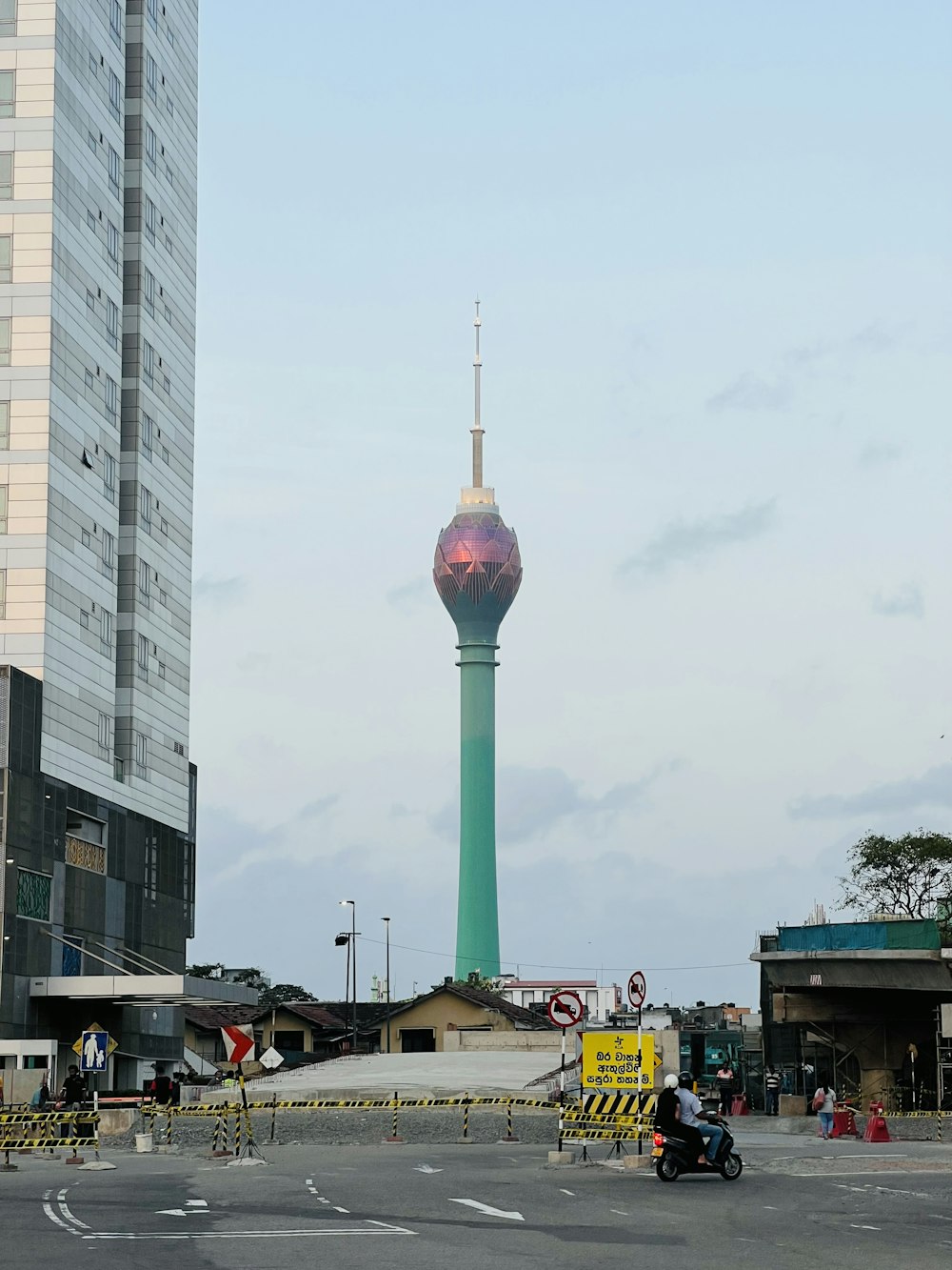 a tall green tower with a sky scraper in the background