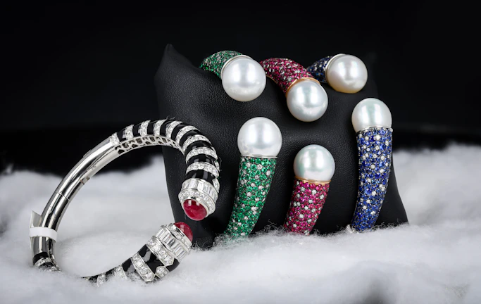 Luxurious bracelet adorned with precious stones showcased on a wooden stand.